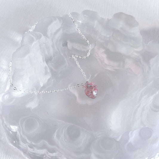Necklace with a pink heart pendant on a white textured surface