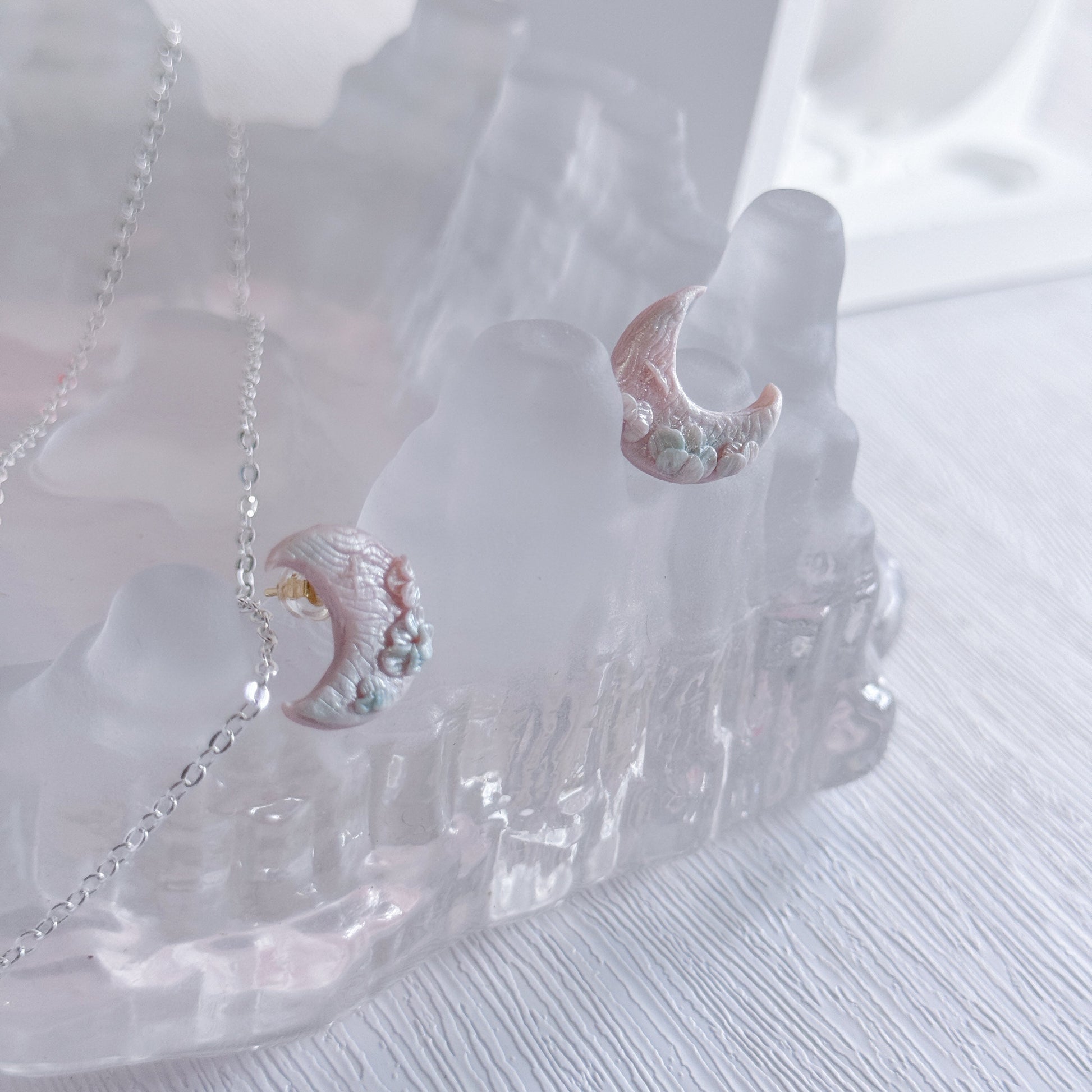 Decorative moon-shaped object with a chain on a white background