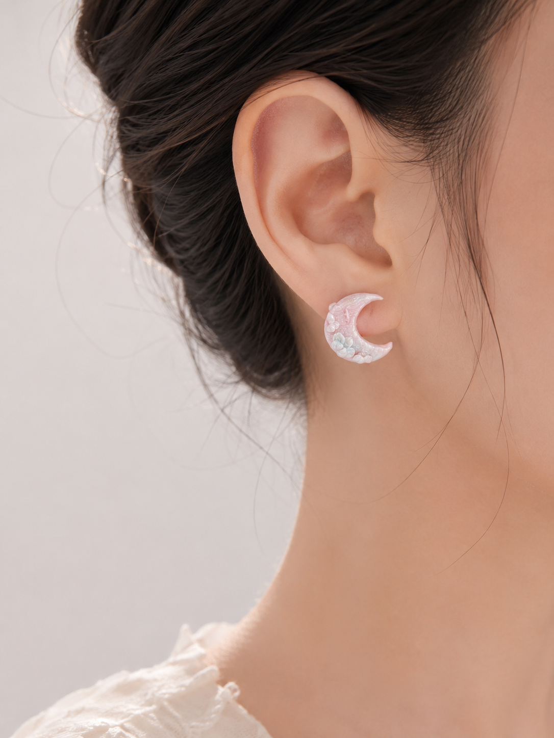 Close-up of an ear wearing a moon-shaped earring with a blurred background
