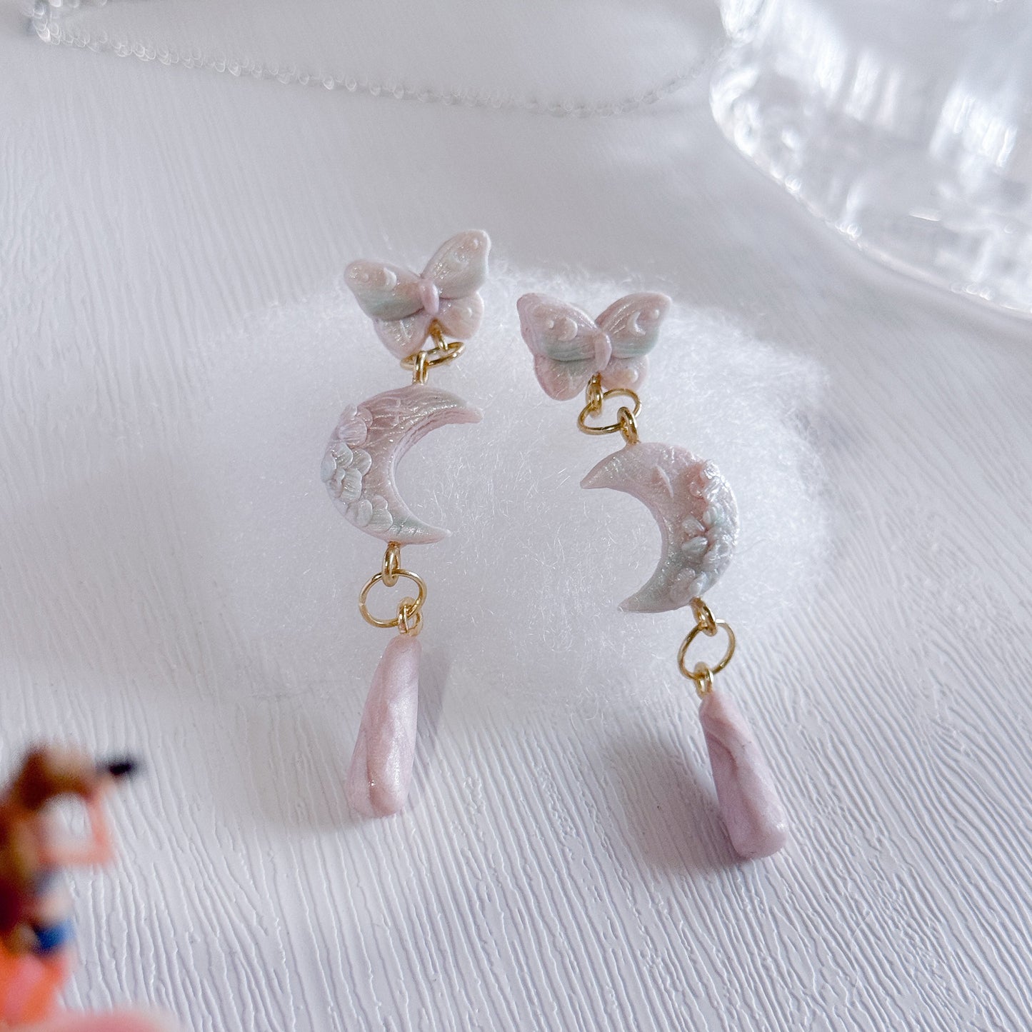 Butterfly-shaped earrings with pink accents on a white surface