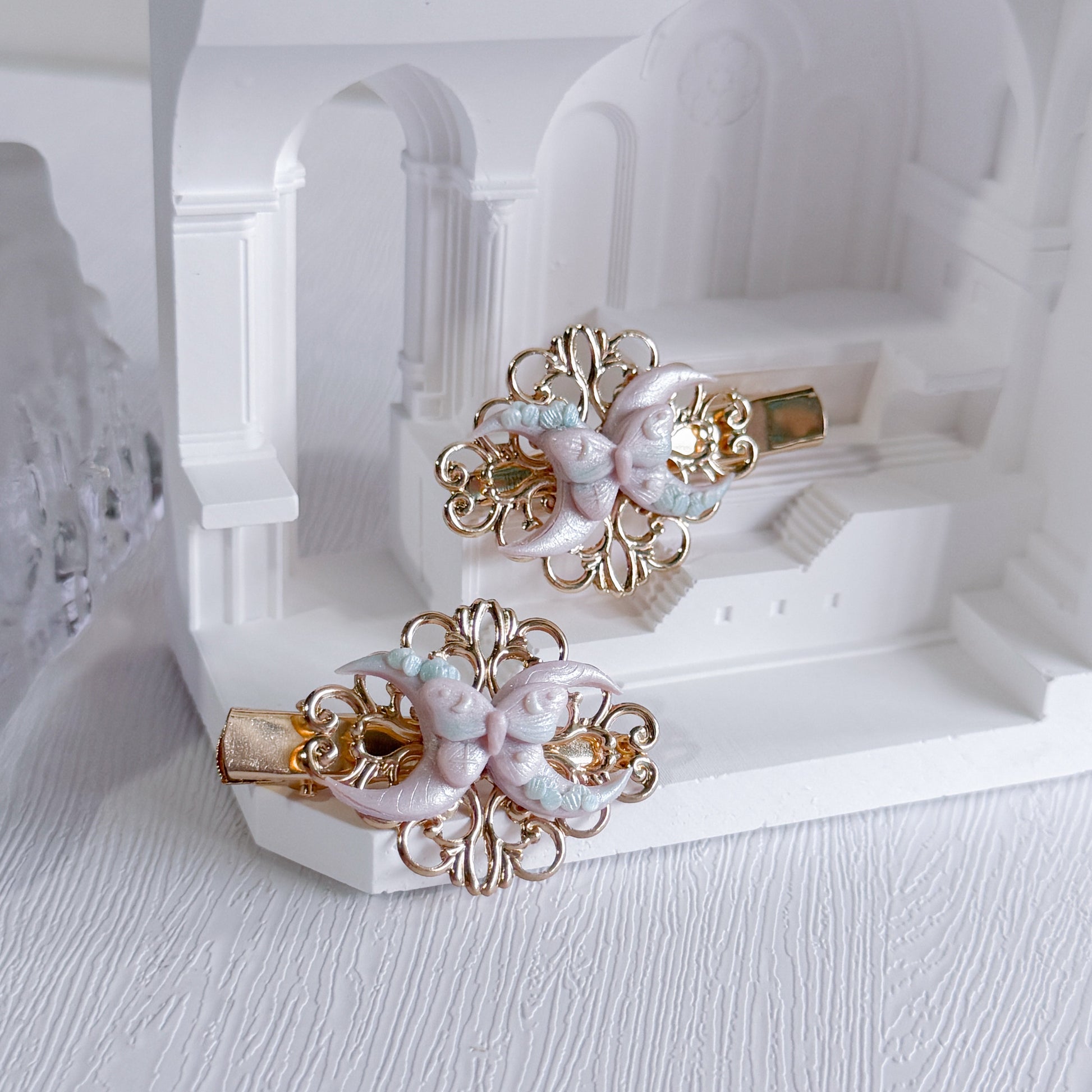 Pair of decorative hair clips on a white stand with a white background