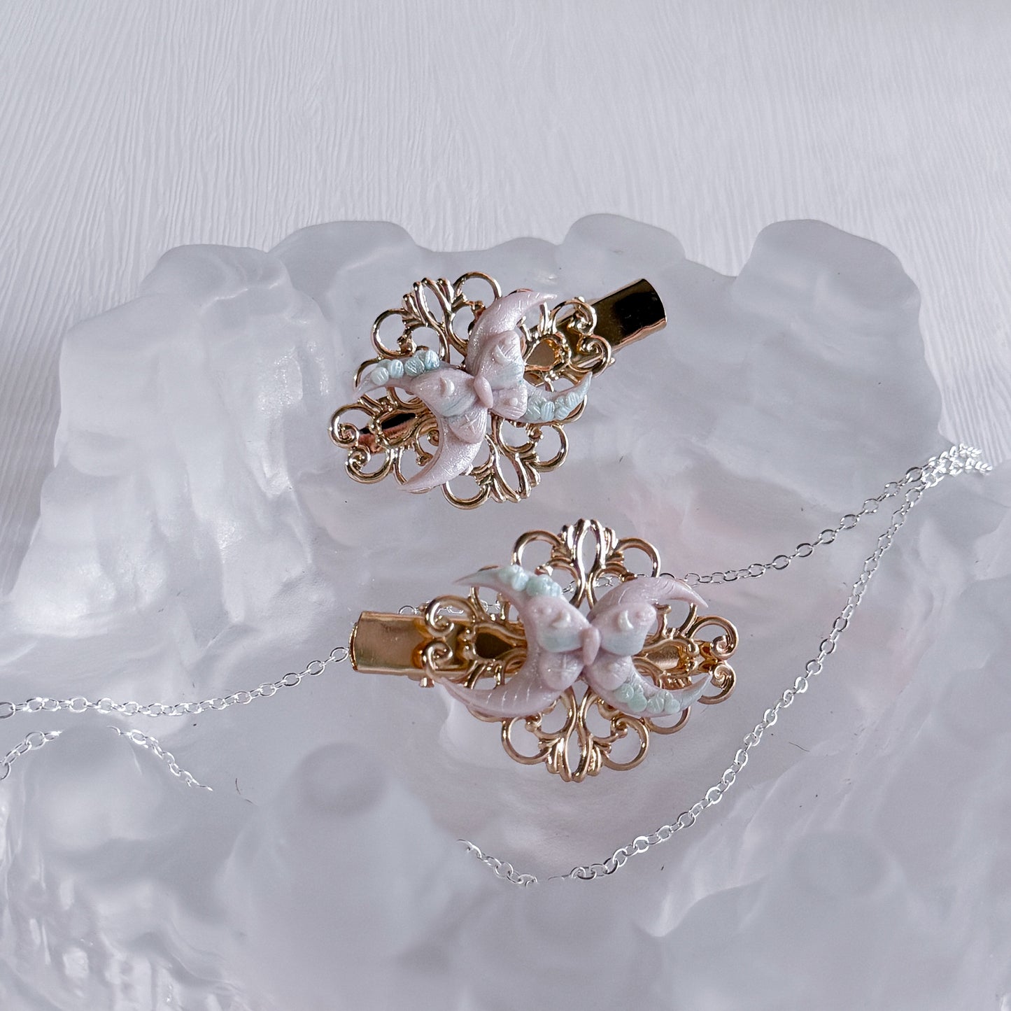 Pair of moon butterflyl hair clips on a textured white surface