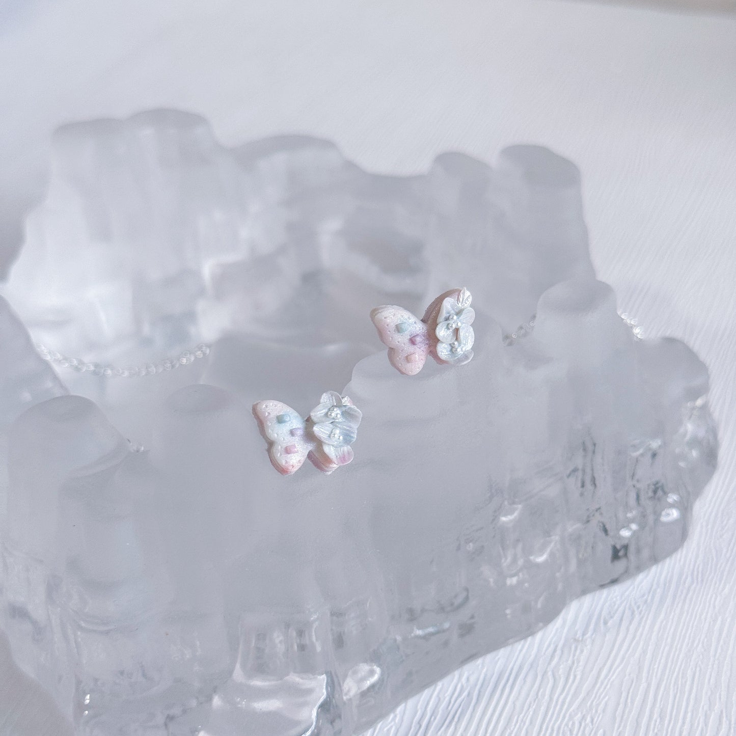 Butterfly-shaped earrings on a textured white surface