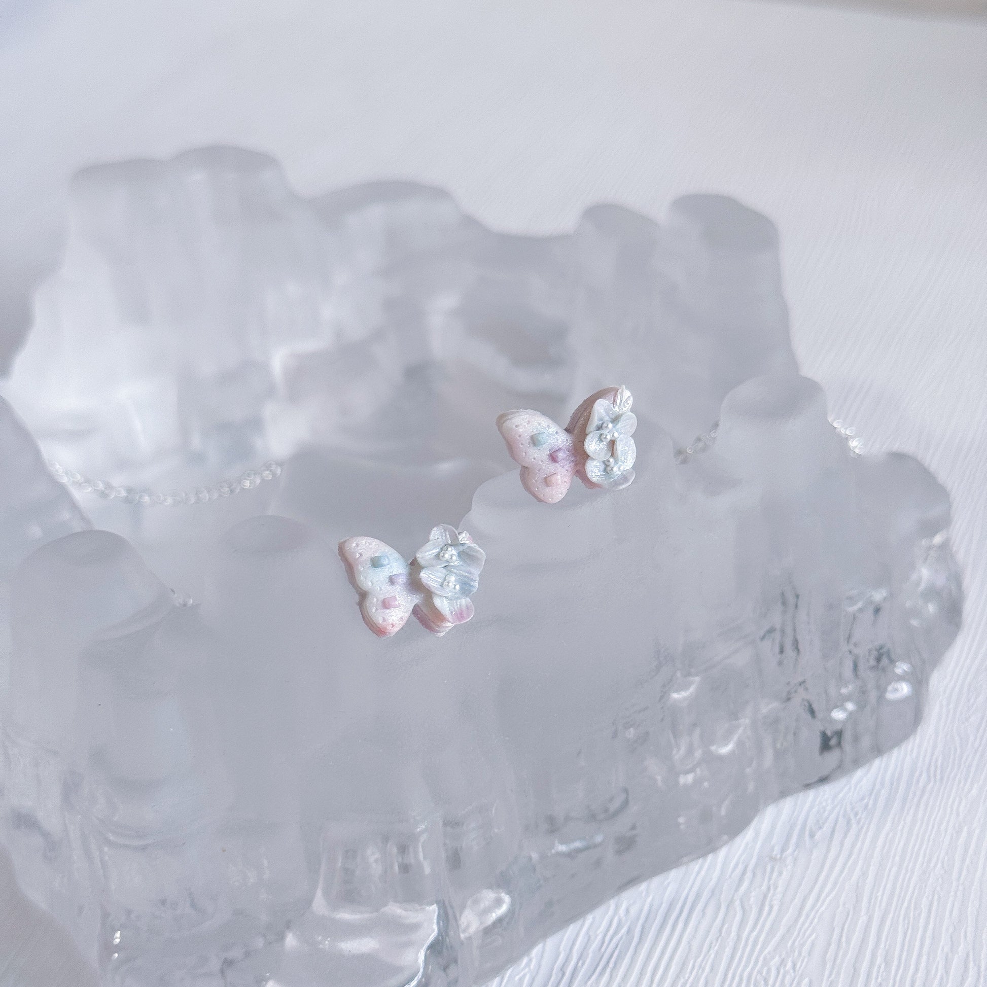Butterfly-shaped earrings on a textured white surface