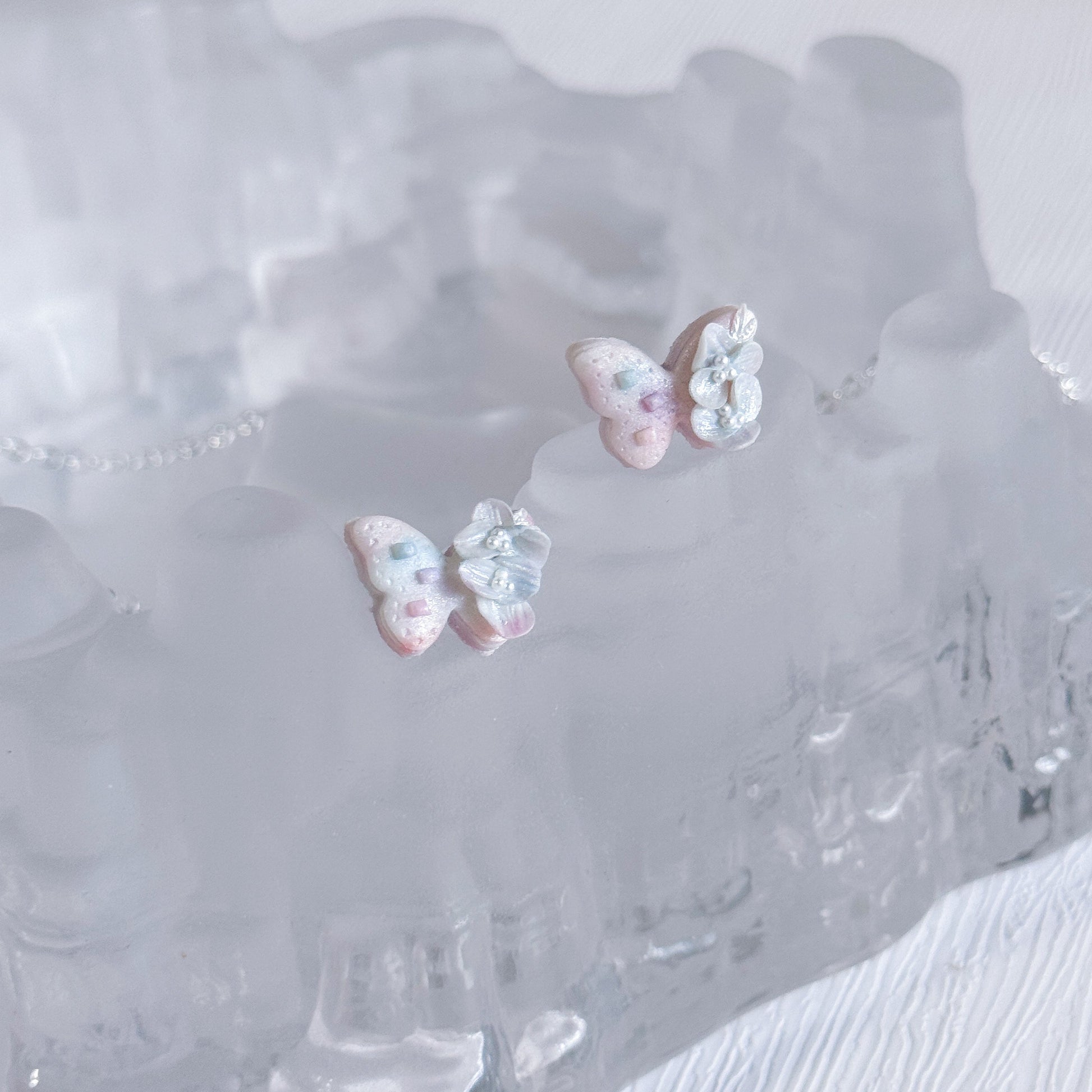 Butterfly-shaped earrings on a clear crystal dish