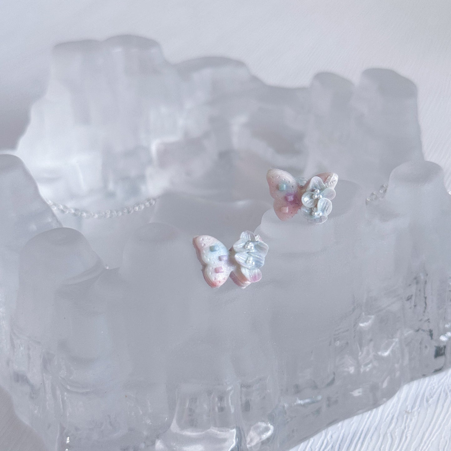 Pair of butterfly-shaped earrings on a clear crystal dish.
