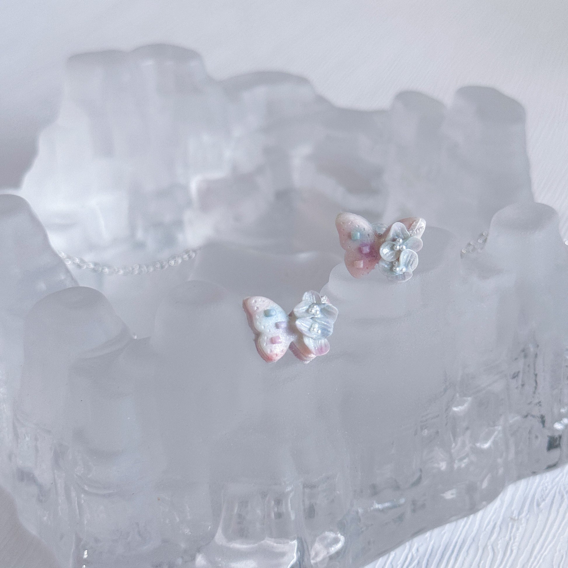 Pair of butterfly-shaped earrings on a clear crystal dish.