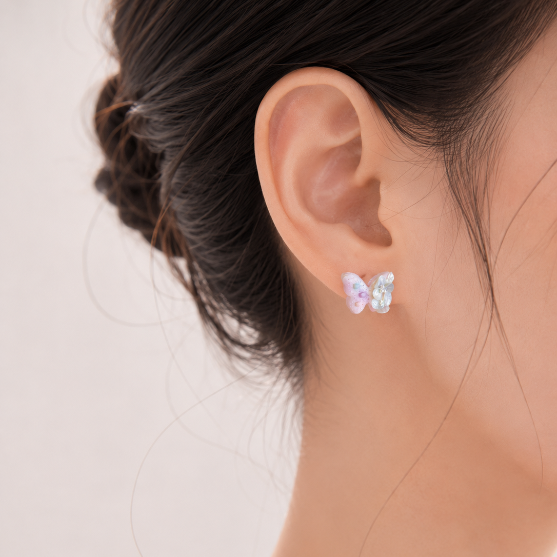Close-up of an ear wearing a butterfly-shaped earring with a blurred background